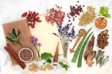 Herbal plant medicine and flower remedy preparation with herbs and flowers with old hemp notebook. Natural health care concept for alternative healing. Top view, flat lay on marble background.