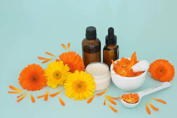 Calendula flowers for skincare with ointment, essential oil bottles and petals in a mortar. Heals wounds, acne, eczema, stimulates collagen, is antiseptic, anti inflammatory, anti bacterial.