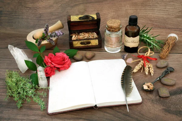 Love potion equipment and magical spell ingredients with notebook, herbs, rose flowers, fertility corn dolly, oil, runes and crystals. Wicca pagan and shamanic tradition for lovers.