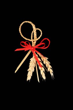 Natural plaited straw corn husk doll. Traditional pagan wiccan fertility symbol used in old fashioned European farming harvest rituals. On black. Top view.