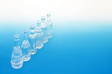 Old fashioned glass bottles in a diagonal line on gradient blue white background. Retro abstract theme creative design concept.