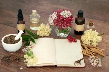 Stress reducing herbal plant medicine with valerian root, ashwagandha and elder flowers and notebook for formulas. For stress reducing natural flower remedies. On rustic wood.