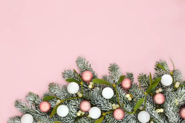 Noel kar köknarı ökseotu arka planında, pastel pembe ve ağaç topu süslemeleri. Kış, Xmas ve Yeni Yıl bayramı için minimum sınır doğası kompozisyonu.