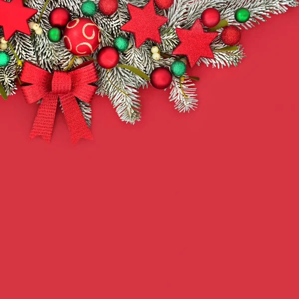 Christmas festive background border with tree decorations and winter fir mistletoe and snow on red background. Vivid composition for Xmas and New year holiday season.