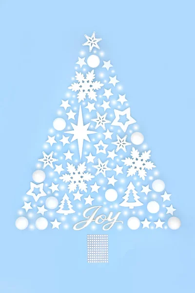 Fantasy Christmas tree concept shape with joy sign, abstract snow, tree bauble star and snowflake ornaments on pastel  blue background. Magical design for winter, Xmas, New Year.