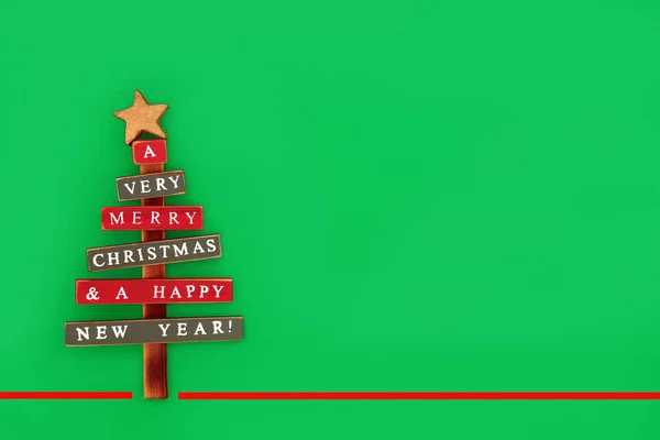 環境に優しいレトロな木造素朴なクリスマスツリー 赤のストライプと緑の背景に古い流行の赤ちゃんの装飾 クリスマスと新年の休暇シーズンのための最小限のデザイン — ストック写真
