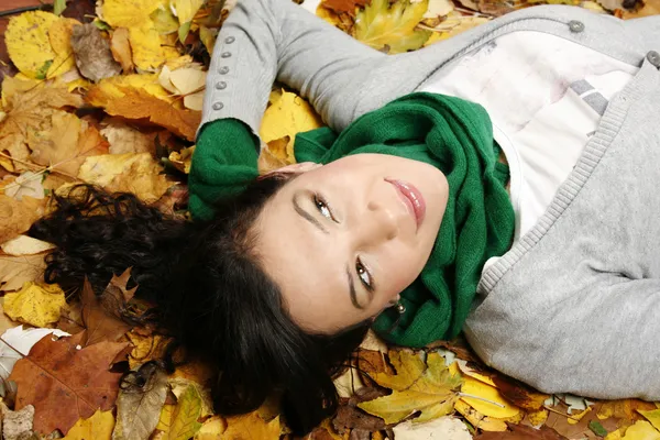 Frau liegt auf Laub im Park — Stockfoto