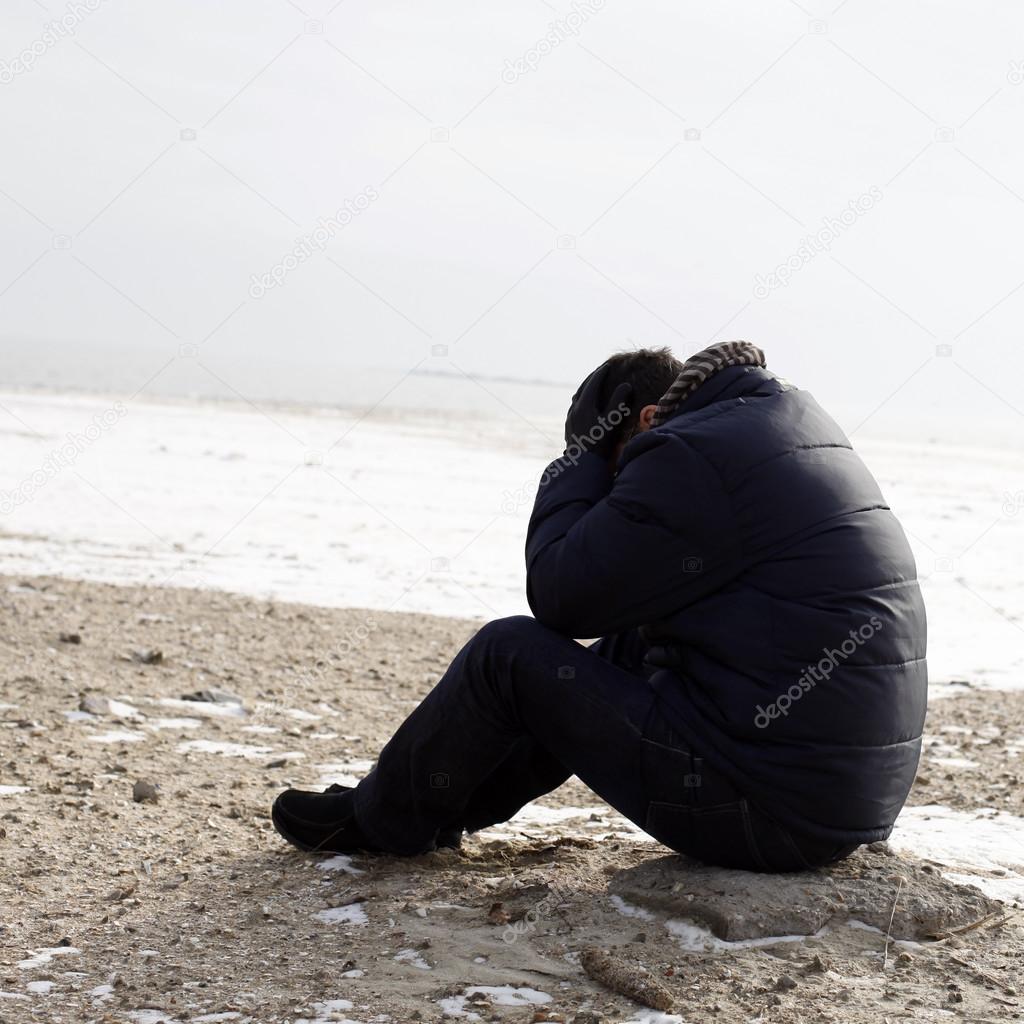 Lonely man sitting on sand