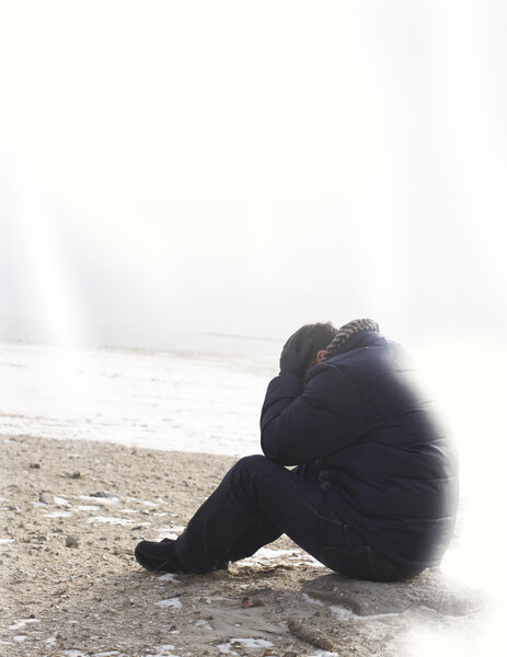 Lonely man sitting on sand