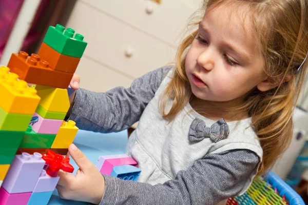 Niña está jugando con ladrillos de construcción —  Fotos de Stock