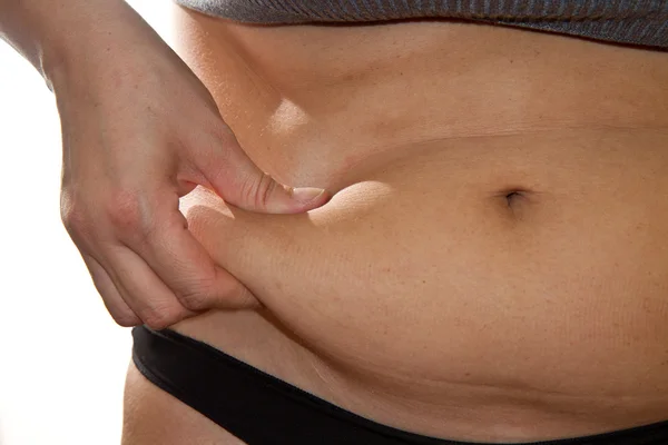 Die Finger der Frau messen ihr Bauchfett — Stockfoto