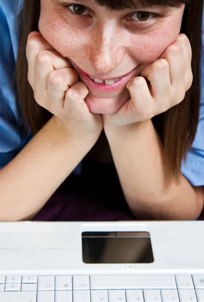 Young woman laying in bed smiling, with laptop compute — Stock Photo, Image