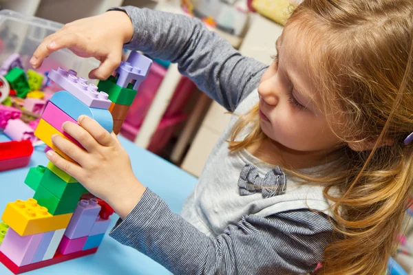 Menina está brincando com tijolos de construção — Fotografia de Stock