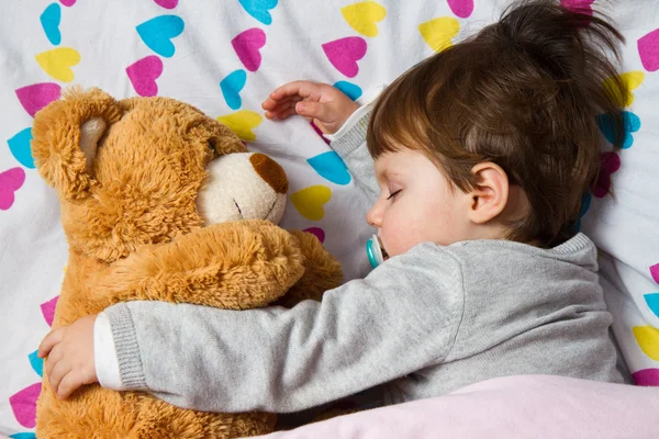 Kind schläft mit Teddybär Stockbild