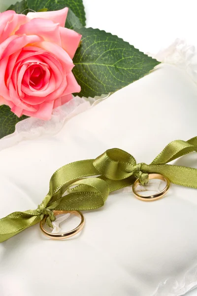 Gold wedding rings on white pillow with rose — Stock Photo, Image