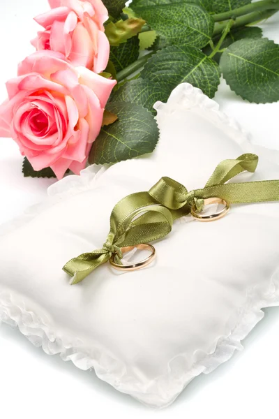 Anillos de boda de oro en almohada blanca con rosa —  Fotos de Stock