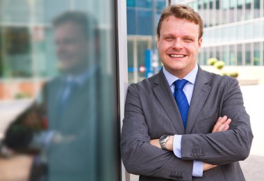 bir binanın önünde duran gülümseyen iş adamı