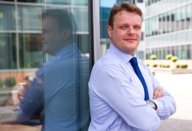 bir binanın önünde duran gülümseyen iş adamı