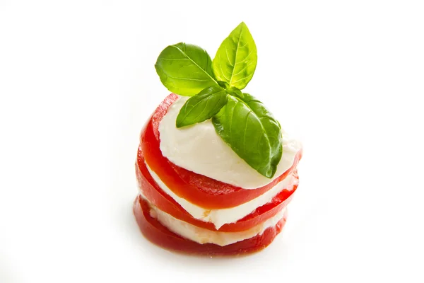 Tomaten und Mozzarella mit Basilikumblättern auf weiß — Stockfoto