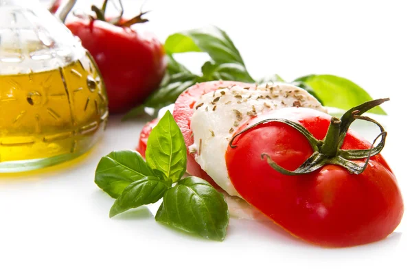 Tomaten und Mozzarella mit Basilikumblättern auf weiß — Stockfoto