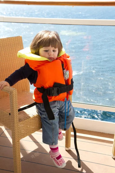 Little girl dressed in life jacket stands in cabin's balcony — Stock Photo, Image