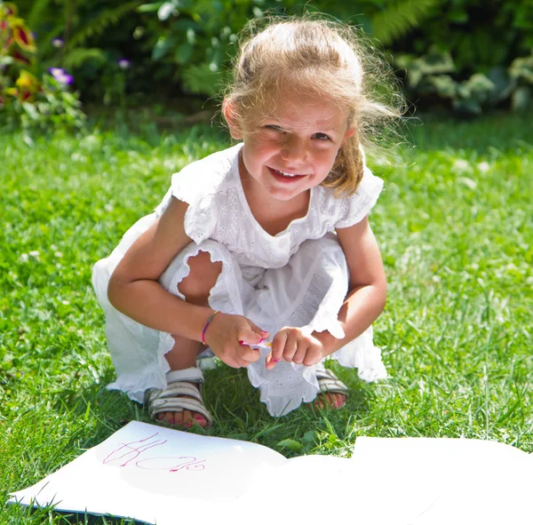 Mädchen zeichnet auf Buch im Gras — Stockfoto