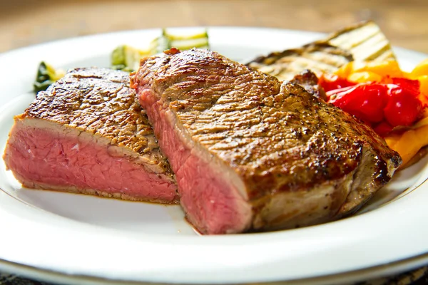 Leckere Rindersteaks auf weißem Teller mit gegrilltem Gemüse — Stockfoto