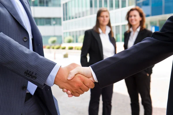 Handshake in front of business people — Stock Photo, Image