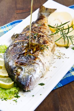 limon ve biberiye tabakta yaldızlı baş çipura ızgara ve