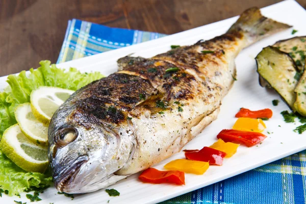 Grilled gilt head sea bream on plate with lemon ,salad and grill — Stock Photo, Image