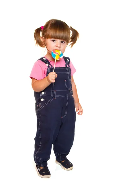Cute little girl eating a colored lollipop — Stock Photo, Image