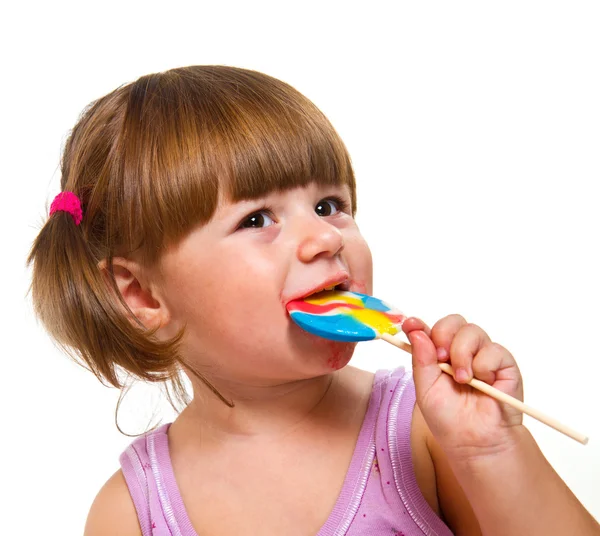 Petite fille mignonne mangeant une sucette colorée — Photo