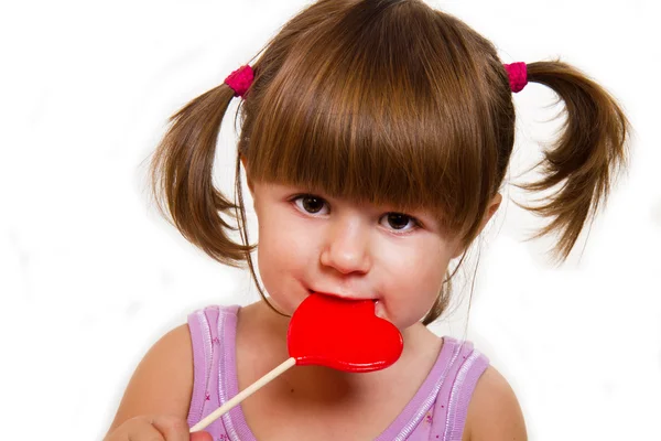 Klein meisje rood hart lollipop eten — Stockfoto