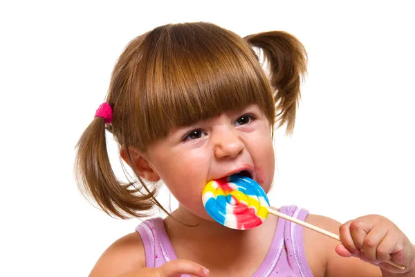 Χαριτωμένο κοριτσάκι που τρώει ένα χρωματιστό γλειφιτζούρι — Φωτογραφία Αρχείου