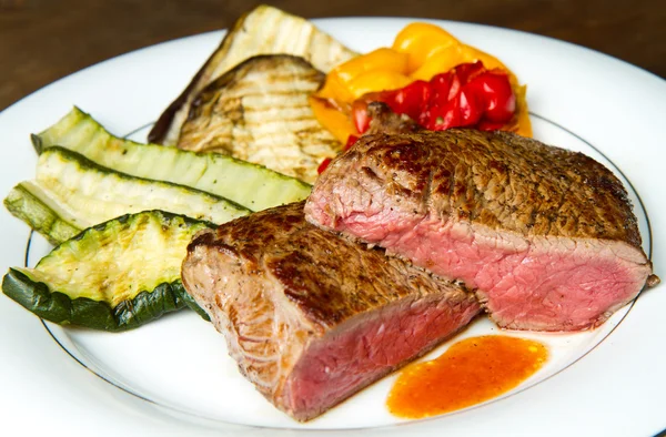 Delicious beef steaks on white dish with grilled vegetables — Stock Photo, Image