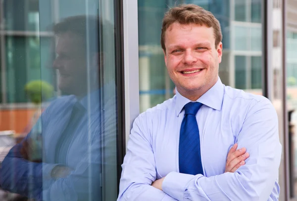 Homme d'affaires souriant debout devant un immeuble — Photo