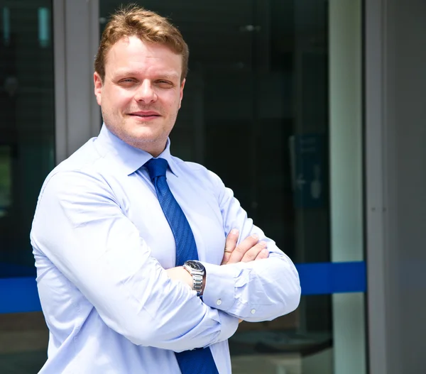 Smiling businessman standing outside a building — Stock Photo, Image