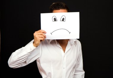 kızgın yüz kartı tutan genç işadamı