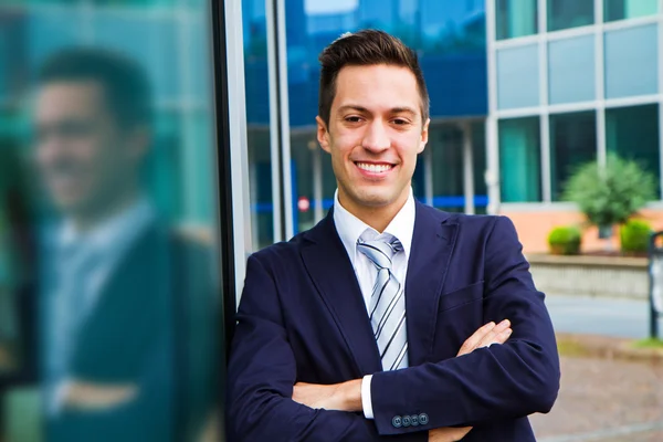 Lächelnder junger Geschäftsmann steht vor einem Gebäude — Stockfoto