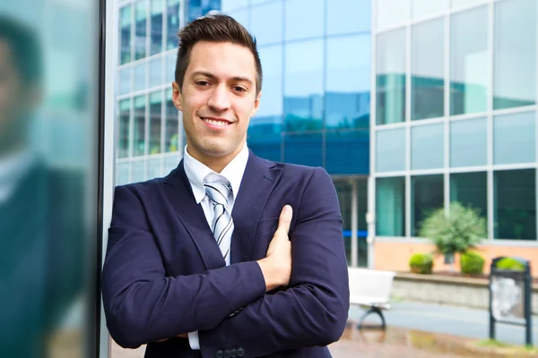 Usměvavý mladý podnikatel stojící mimo budovu — Stock fotografie