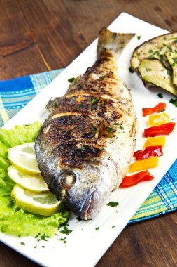 limon, salata ve ızgara plakası üzerinde yan kafa çipura ızgara