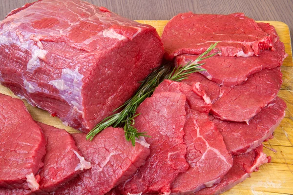 Enorme pedaço de carne vermelha e bife na mesa de madeira — Fotografia de Stock