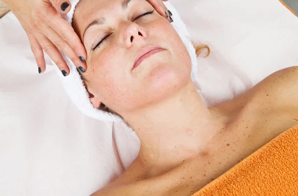Bella giovane donna che riceve massaggio facciale con gli occhi chiusi — Foto Stock