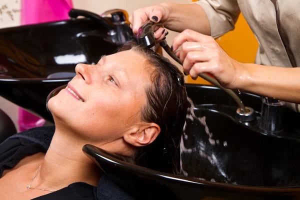 Parrucchieri lavaggio a mano capelli di cliente femminile in salone — Foto Stock