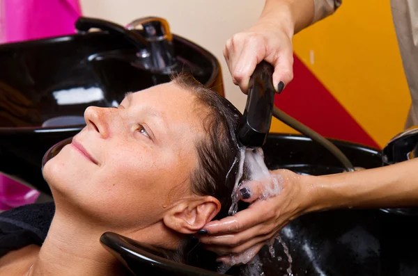 Hairdressers hand washing female customer's hair in salon — Stock Photo, Image