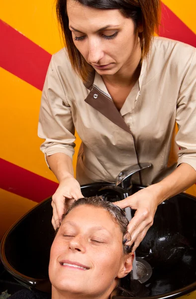 Hairdressers hand washing female customer's hair in salon — Stock Photo, Image