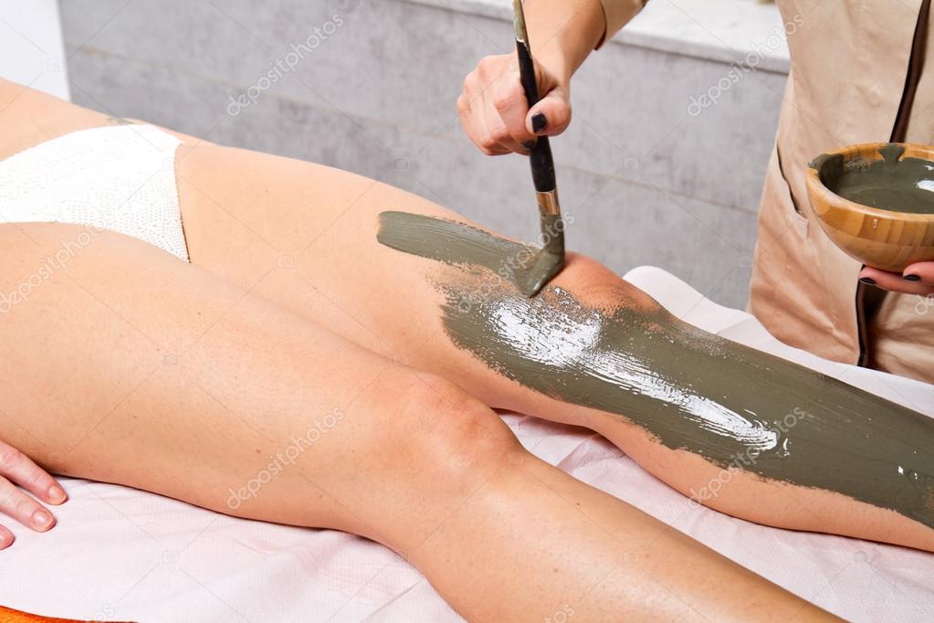 relaxing woman lying on a massage table receiving a mud treatmen