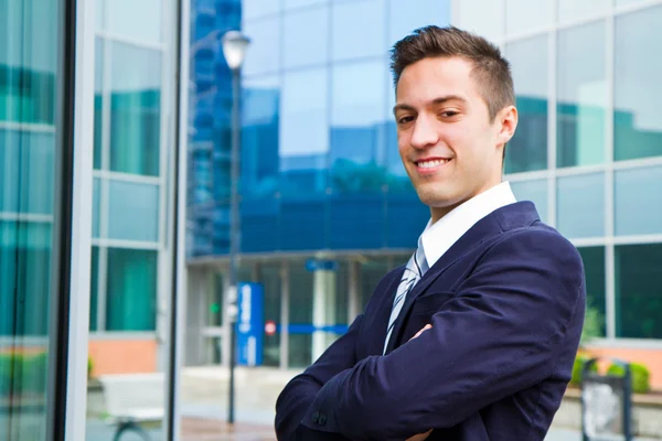 Smiling young businessman standing outside a building — Stock Photo, Image