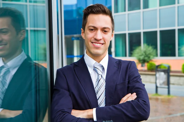 Smiling young businessman standing outside a building — Stock Photo, Image