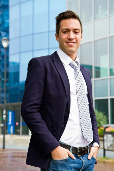 Smiling young businessman standing outside a building — Stock Photo, Image